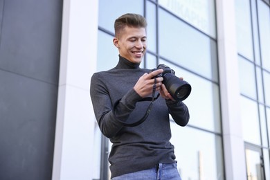 Professional photographer with camera near building outdoors