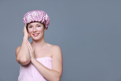 Happy woman in shower cap on grey background, space for text