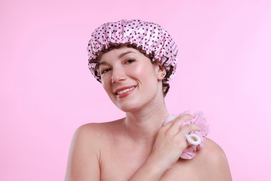 Woman with shower cap and mesh sponge on pink background