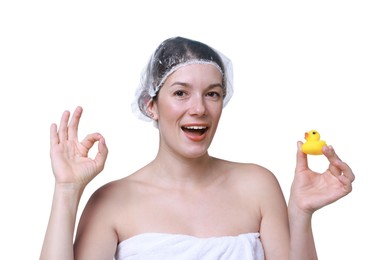 Photo of Woman with shower cap and bath duck showing ok gesture on white background