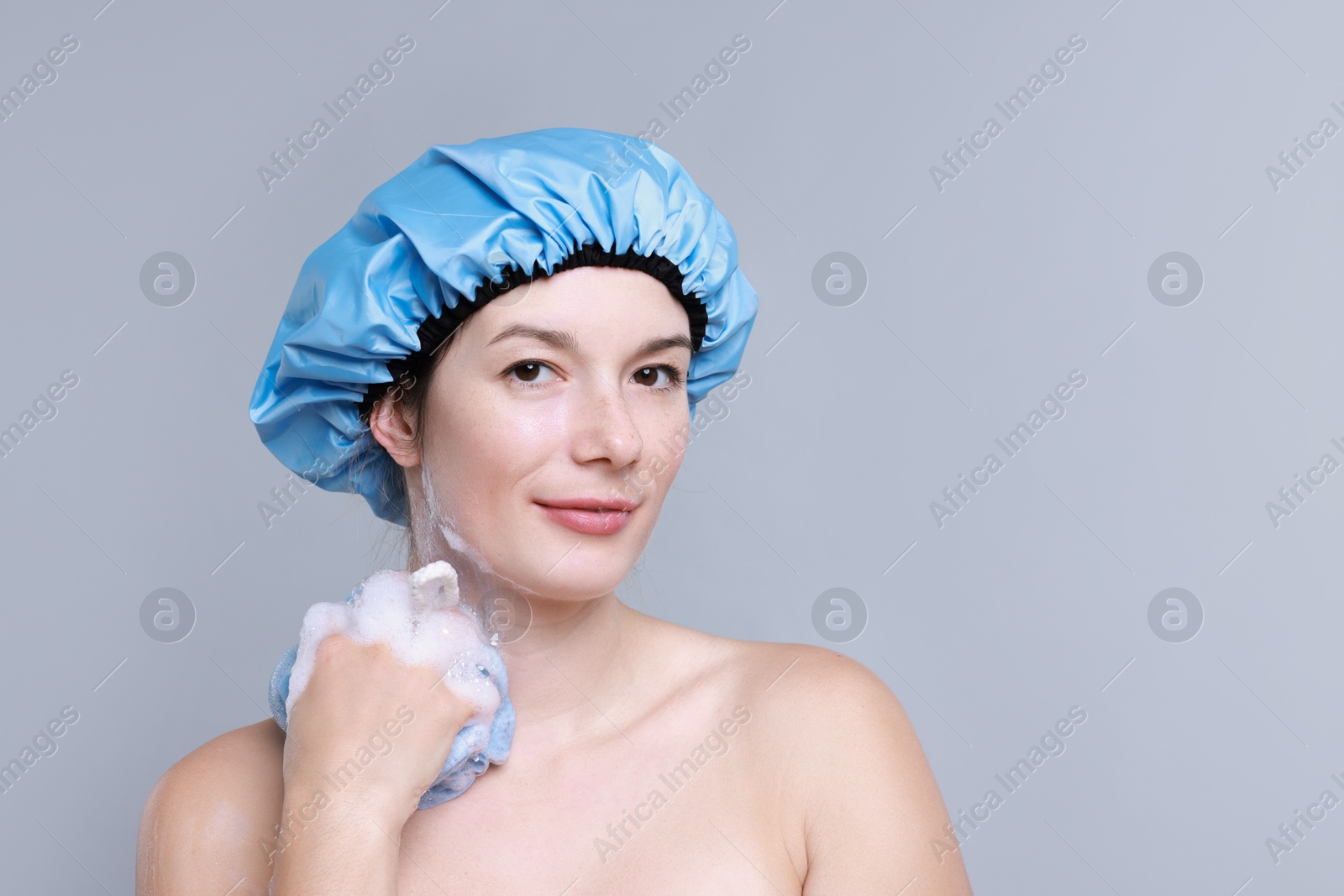 Photo of Woman with shower cap and mesh sponge on grey background