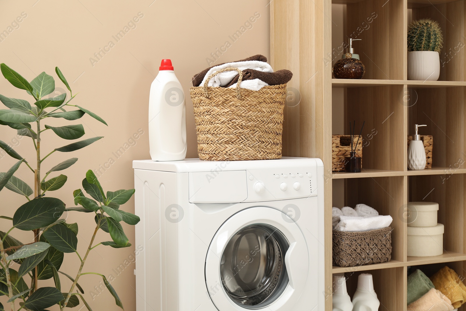 Photo of Wicker basket full of laundry, washing machine and detergent in bathroom