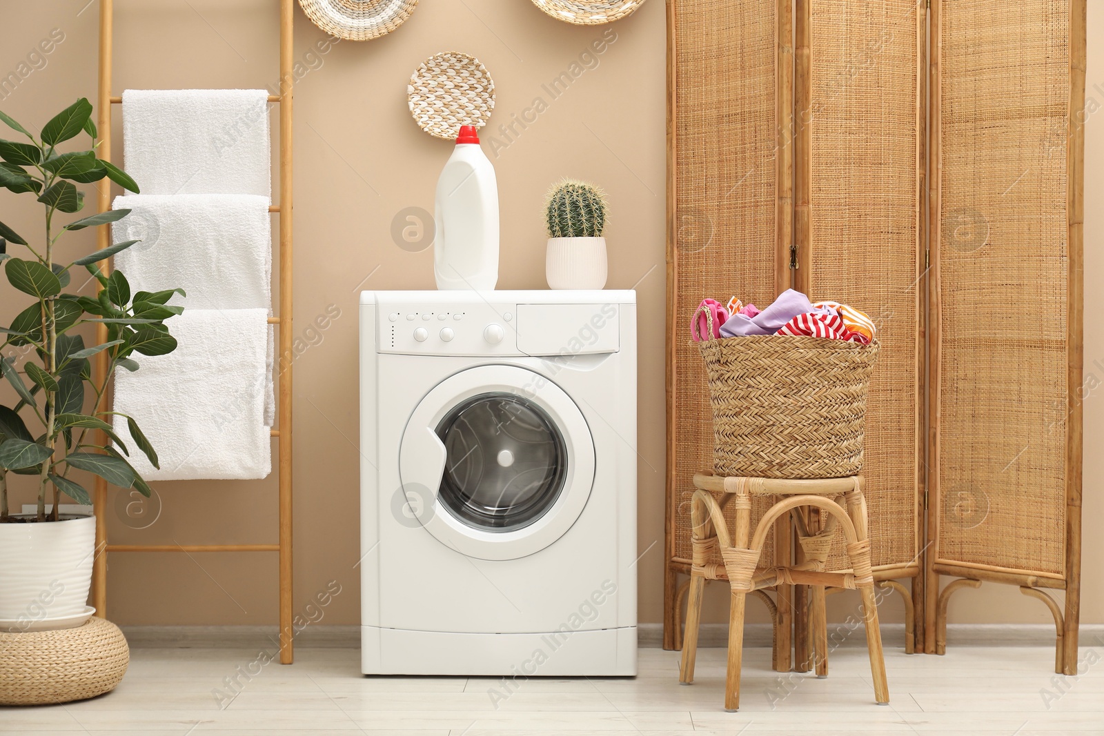 Photo of Wicker basket full of laundry, washing machine and detergent in bathroom