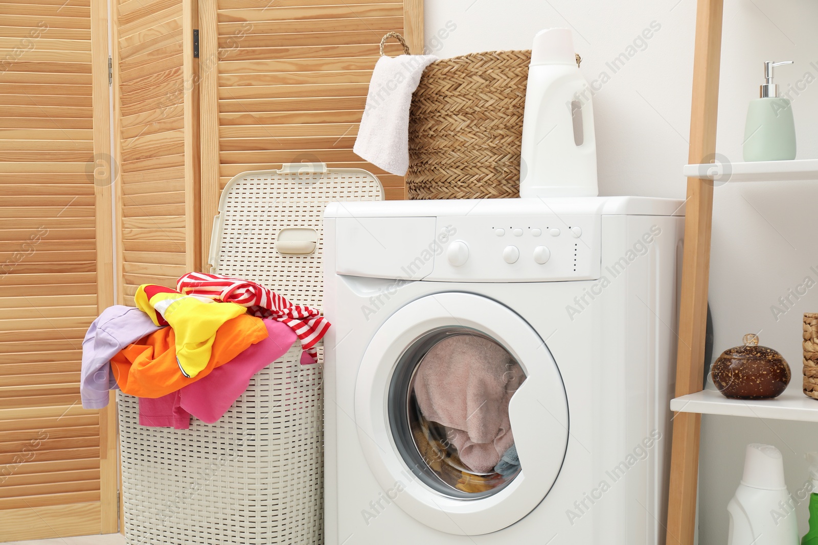 Photo of Wicker baskets with laundry and washing machine in bathroom