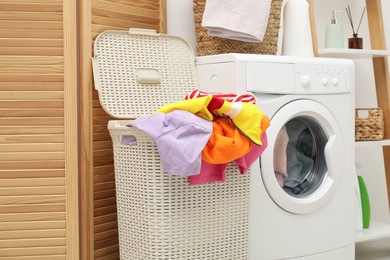 Photo of Wicker baskets with laundry and washing machine in bathroom