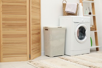 Photo of Wicker laundry baskets, washing machine and detergent in bathroom