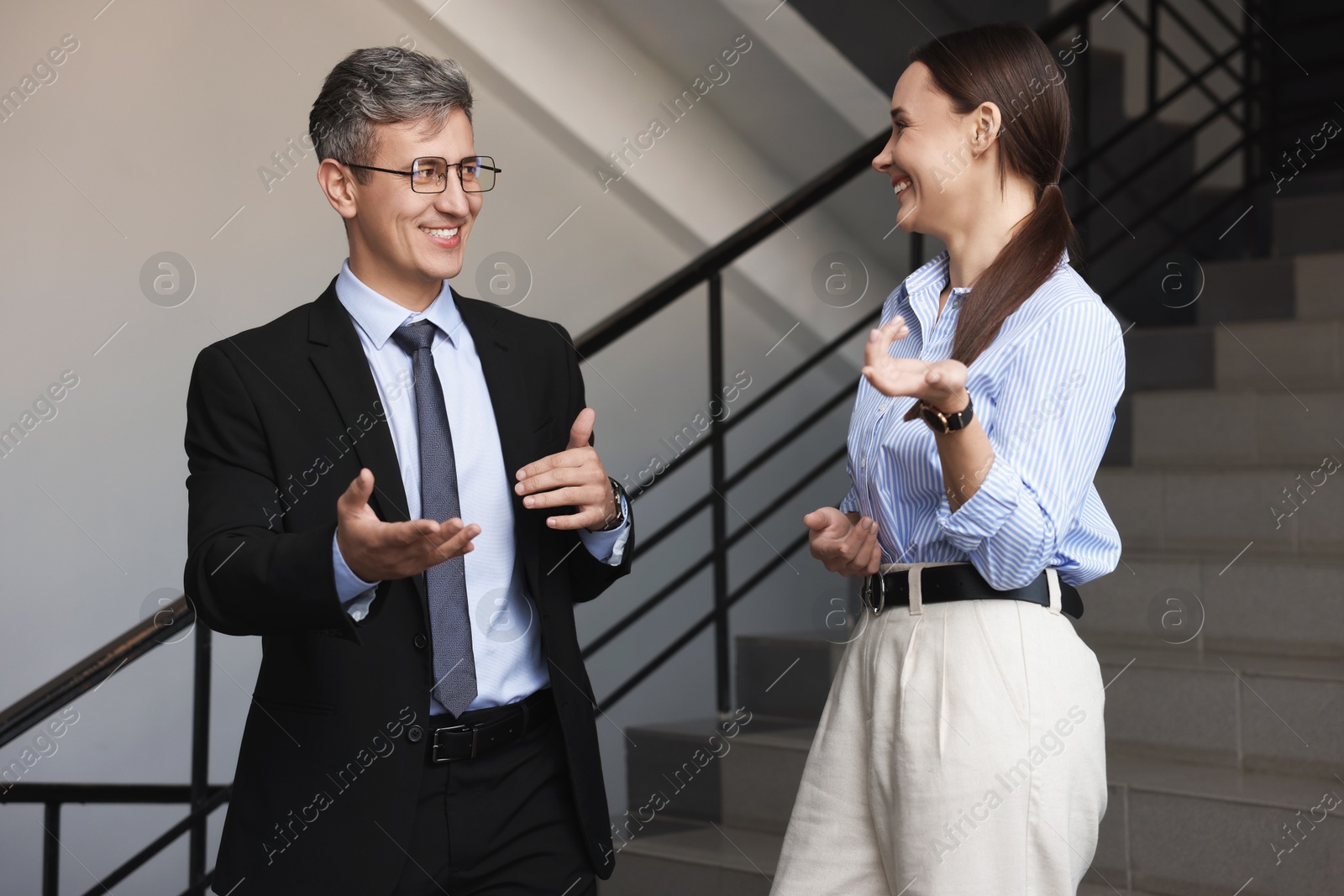 Photo of Coworkers talking while going down stairs in office