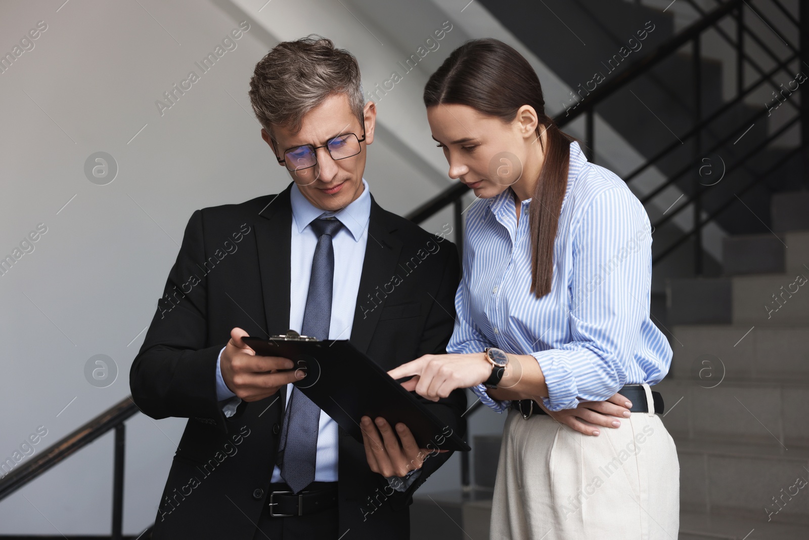 Photo of Coworkers with clipboard on stairs in office