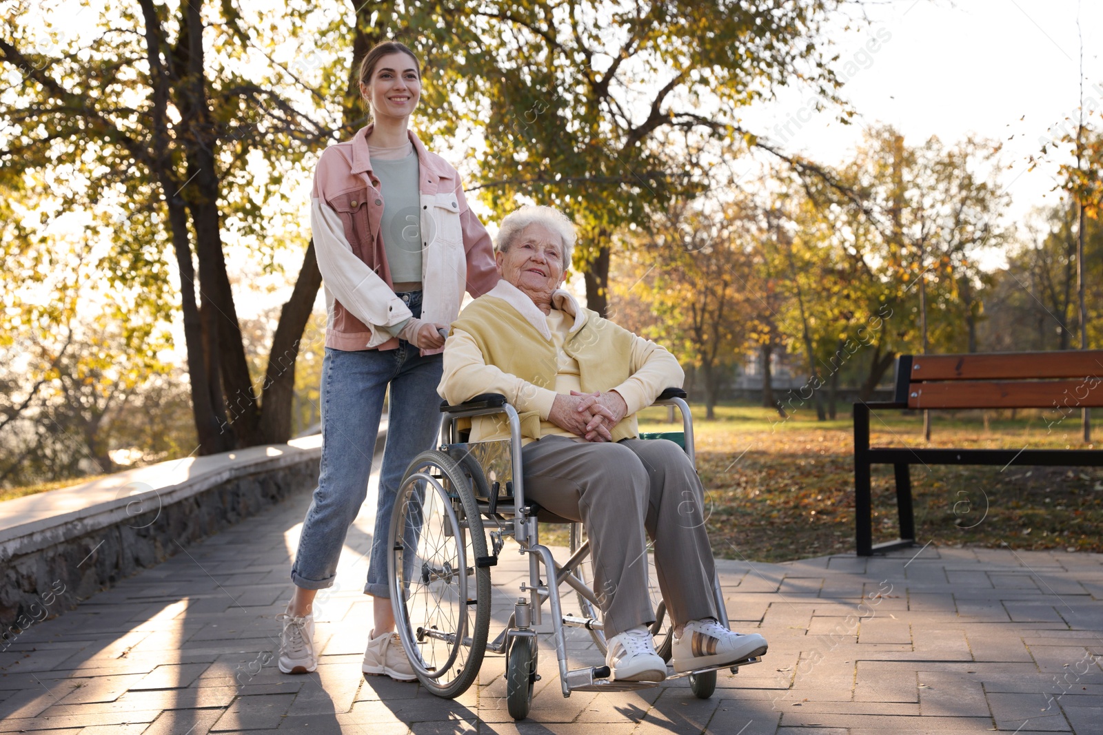 Photo of Caregiver with elderly woman in wheelchair at park