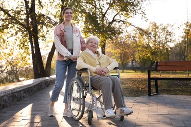 Photo of Caregiver with elderly woman in wheelchair at park