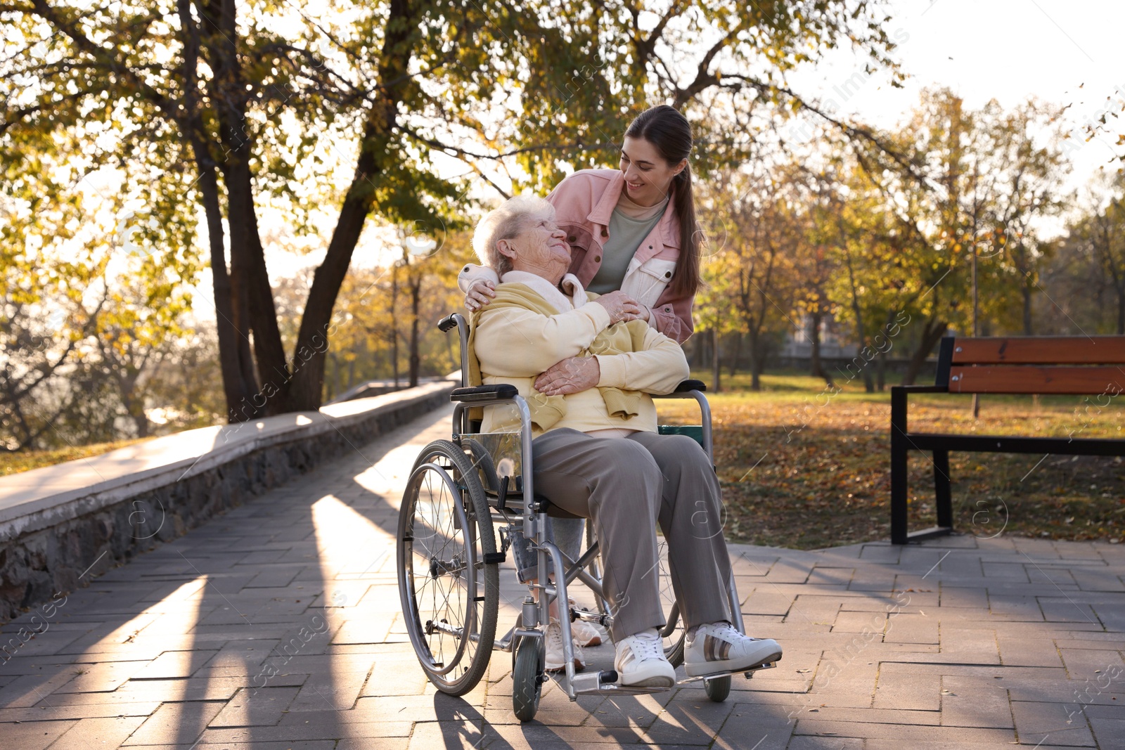 Photo of Caregiver with elderly woman in wheelchair at park