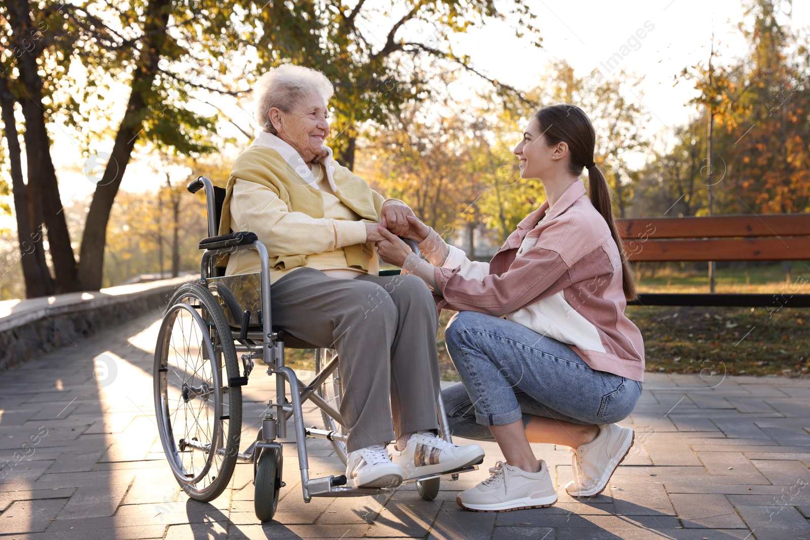 Photo of Caregiver with elderly woman in wheelchair at park