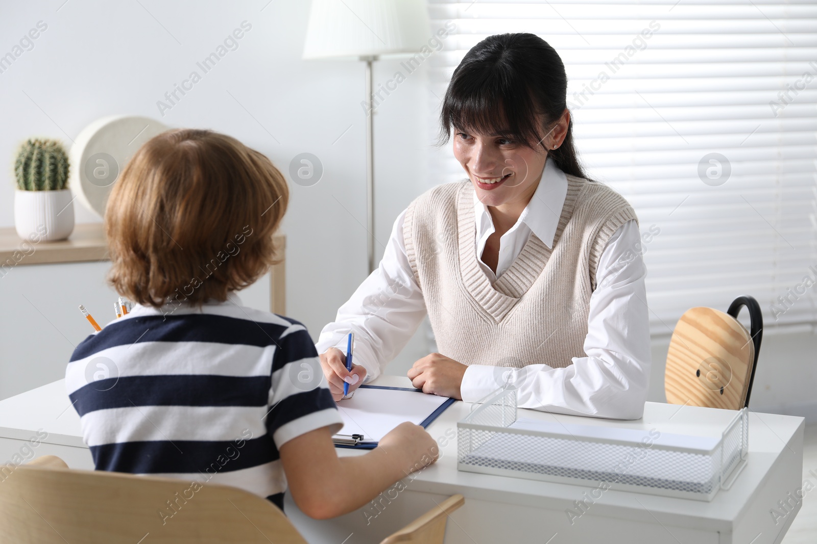 Photo of Little boy having consultation with psychologist in office