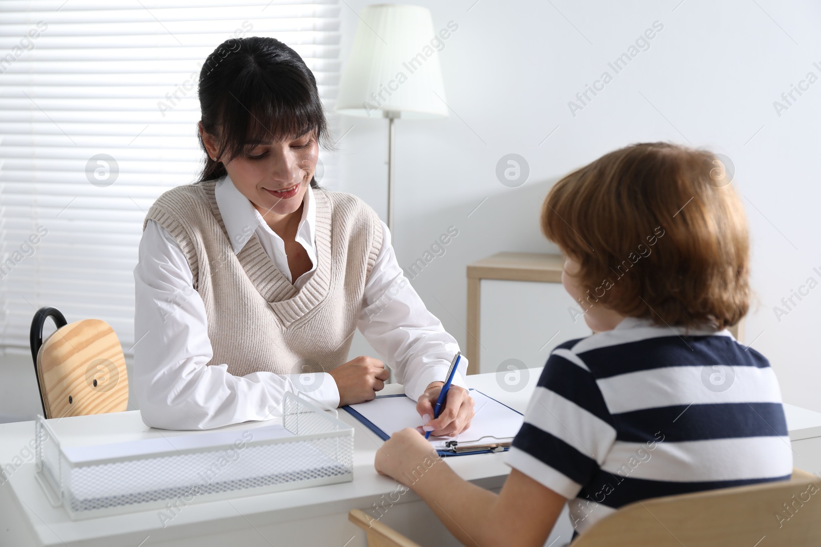 Photo of Little boy having consultation with psychologist in office