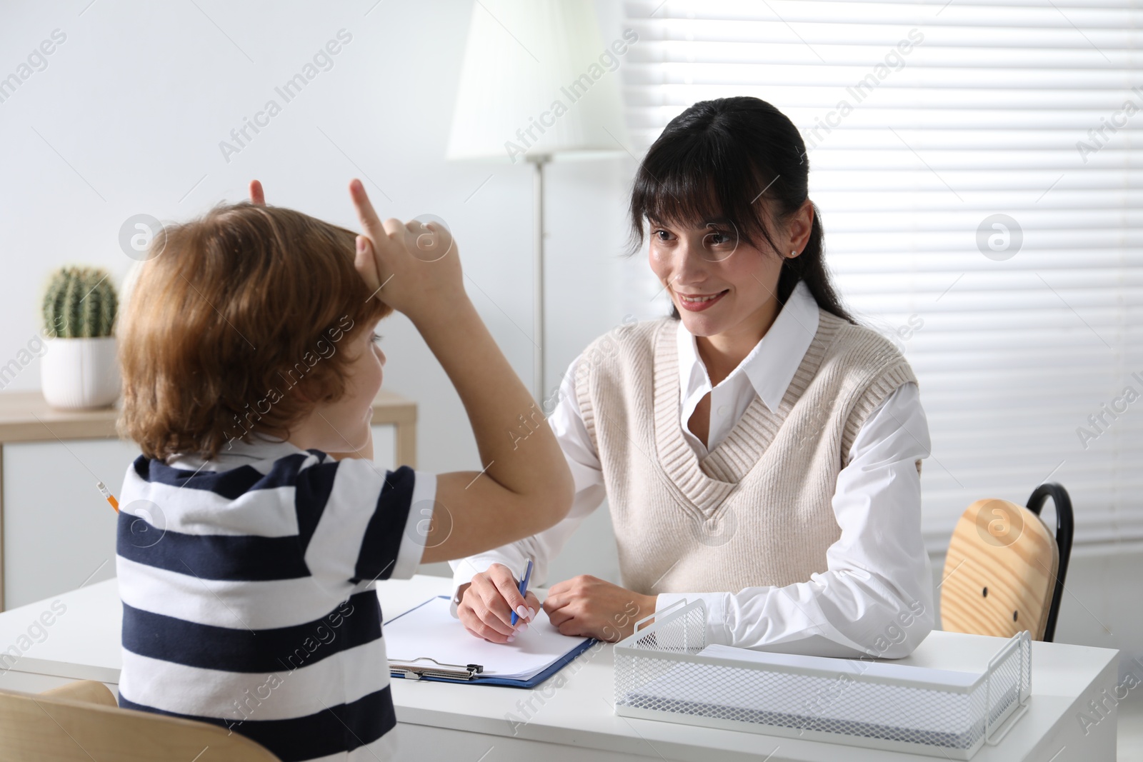 Photo of Little boy having consultation with psychologist in office