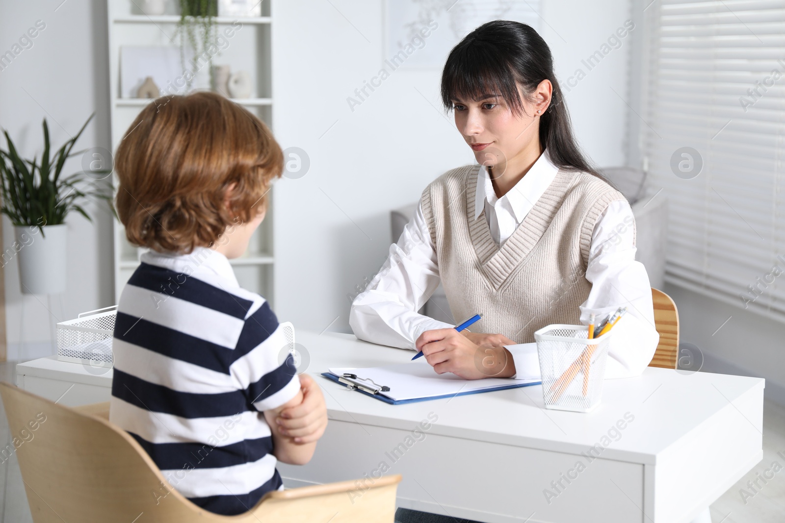 Photo of Little boy having consultation with psychologist in office