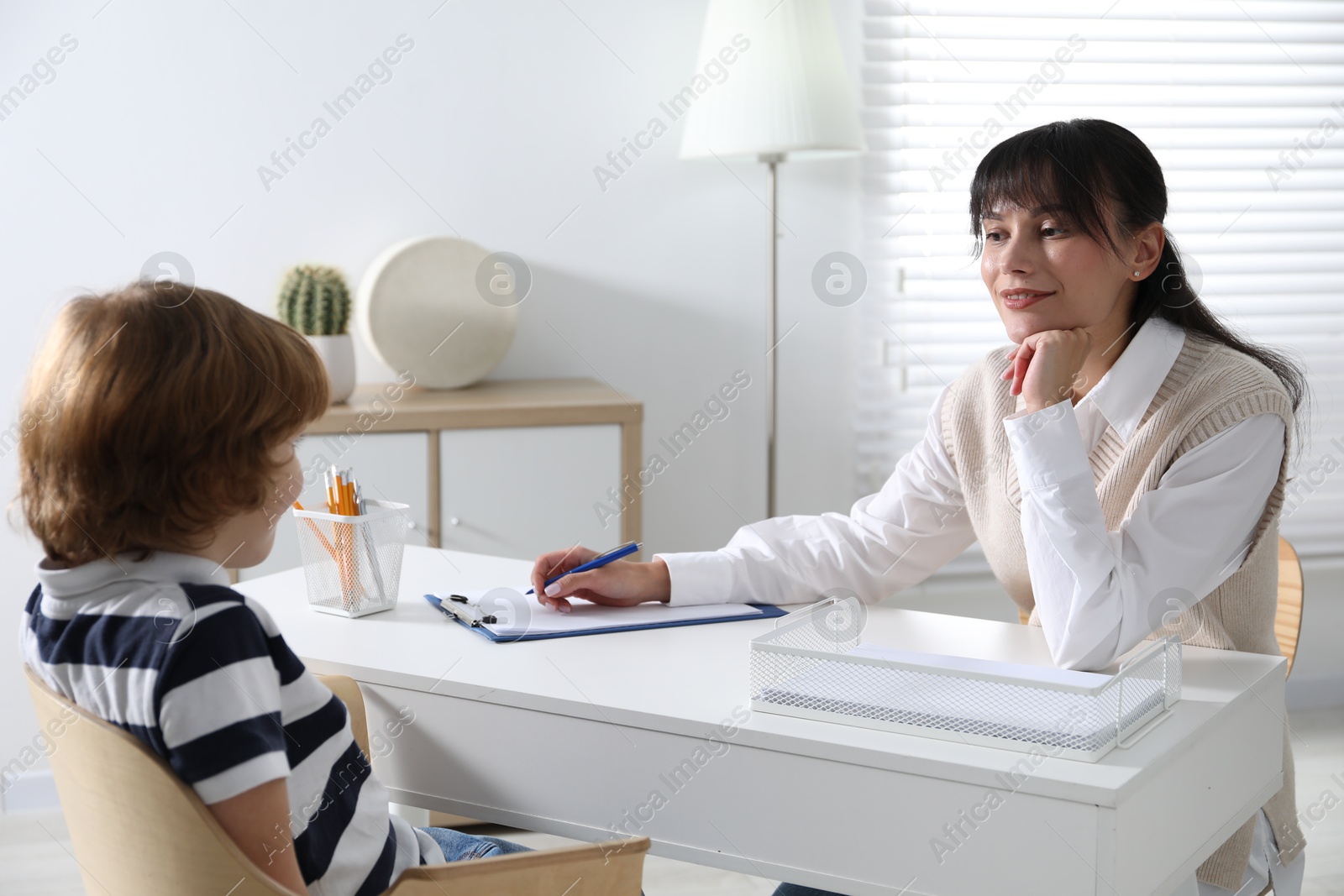 Photo of Little boy having consultation with psychologist in office