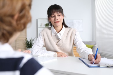 Photo of Little boy having consultation with psychologist in office, selective focus