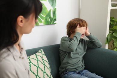 Upset little boy having therapy session with psychologist in office