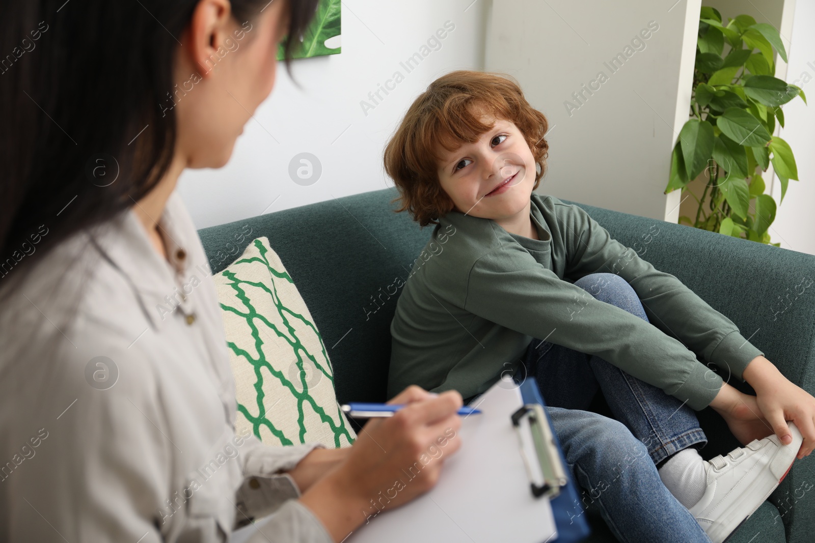 Photo of Little boy having therapy session with psychologist in office