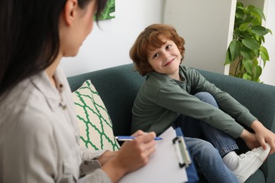 Photo of Little boy having therapy session with psychologist in office