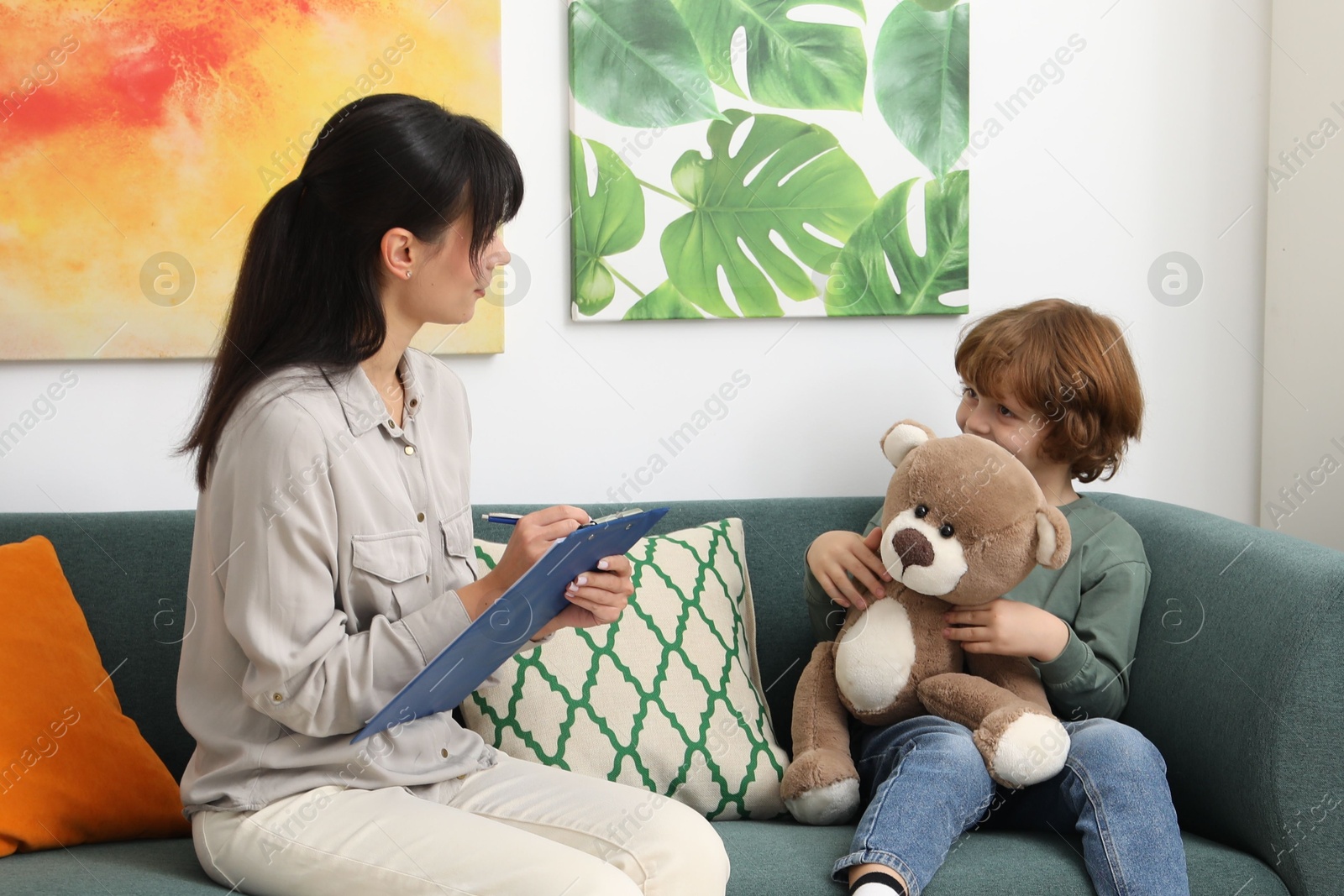 Photo of Little boy having therapy session with psychologist in office