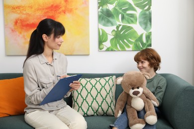 Photo of Little boy having therapy session with psychologist in office