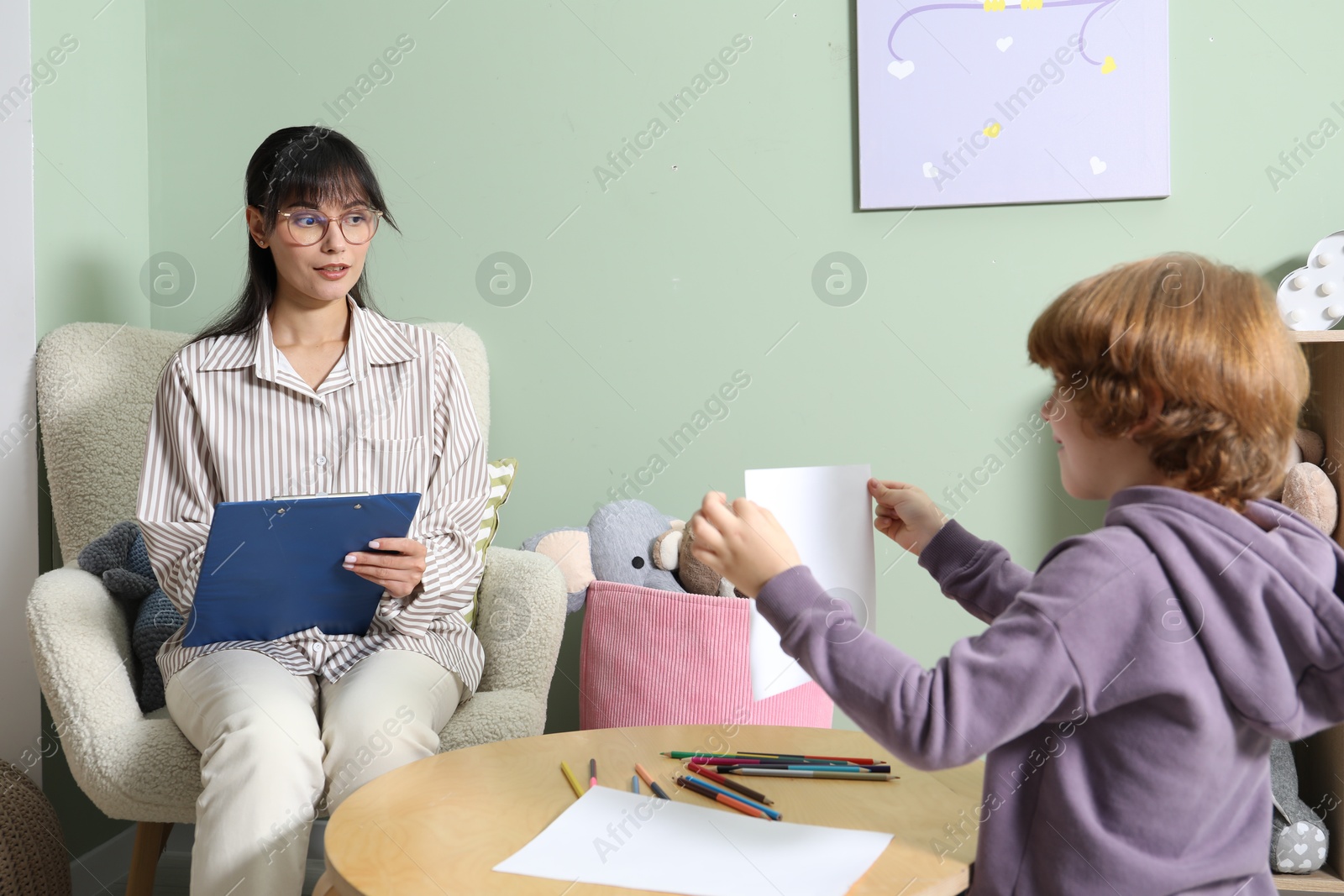 Photo of Psychologist evaluating boy's cognitive functions in office