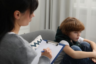 Photo of Little boy having therapy session with psychologist in office