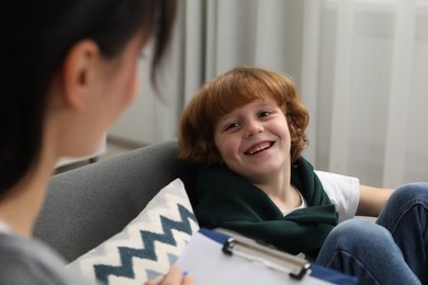 Photo of Little boy having therapy session with psychologist in office