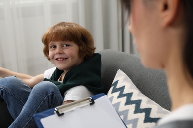 Photo of Little boy having therapy session with psychologist in office