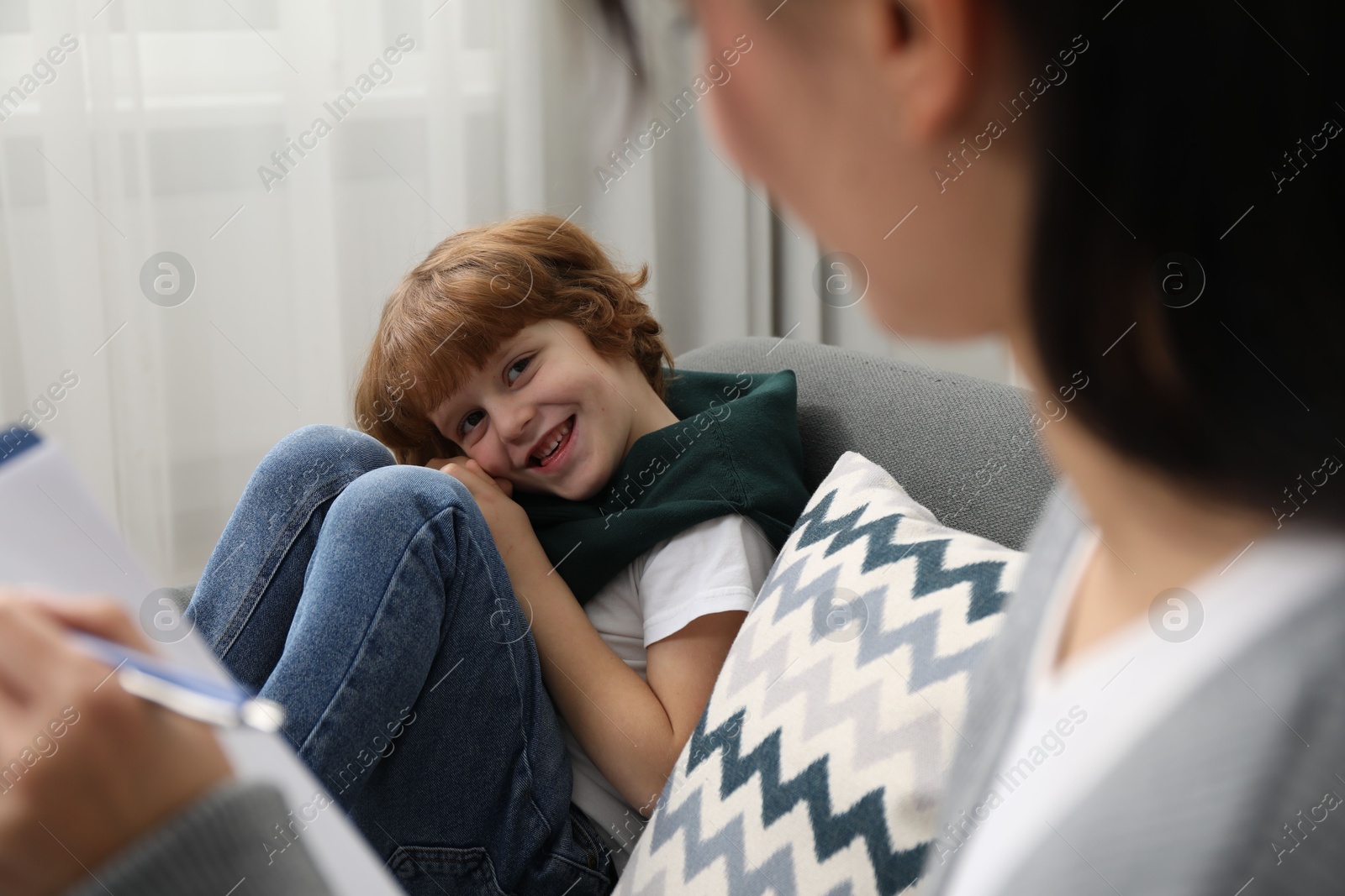 Photo of Little boy having therapy session with psychologist in office