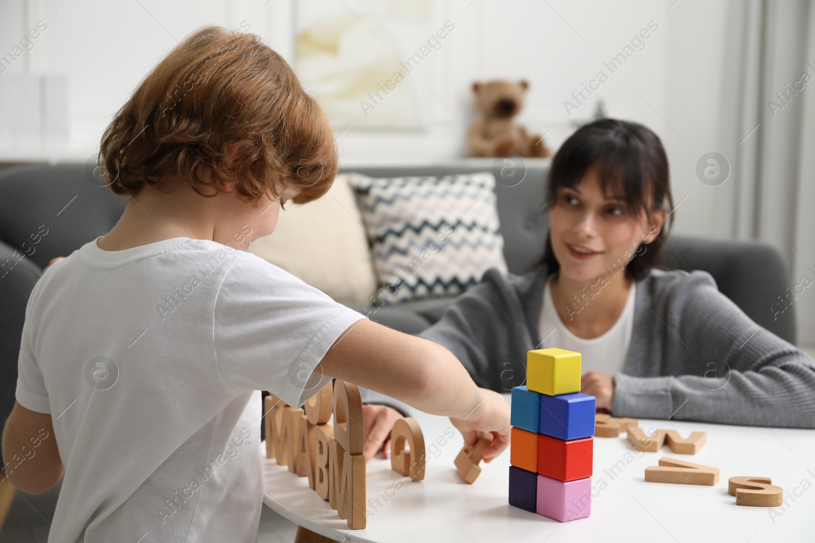 Photo of Psychologist evaluating boy's cognitive functions at table in office, selective focus