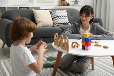 Psychologist evaluating boy's cognitive functions at table in office, selective focus