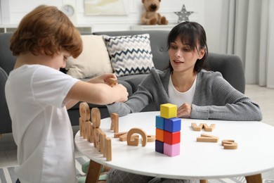 Photo of Psychologist evaluating boy's cognitive functions at table in office, selective focus