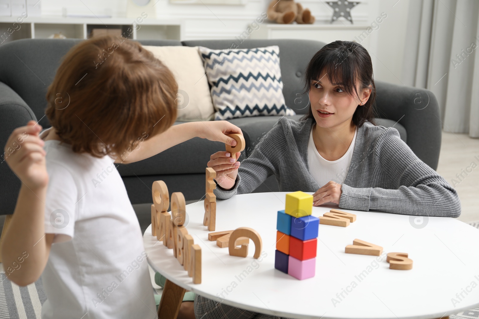 Photo of Psychologist evaluating boy's cognitive functions at table in office, selective focus