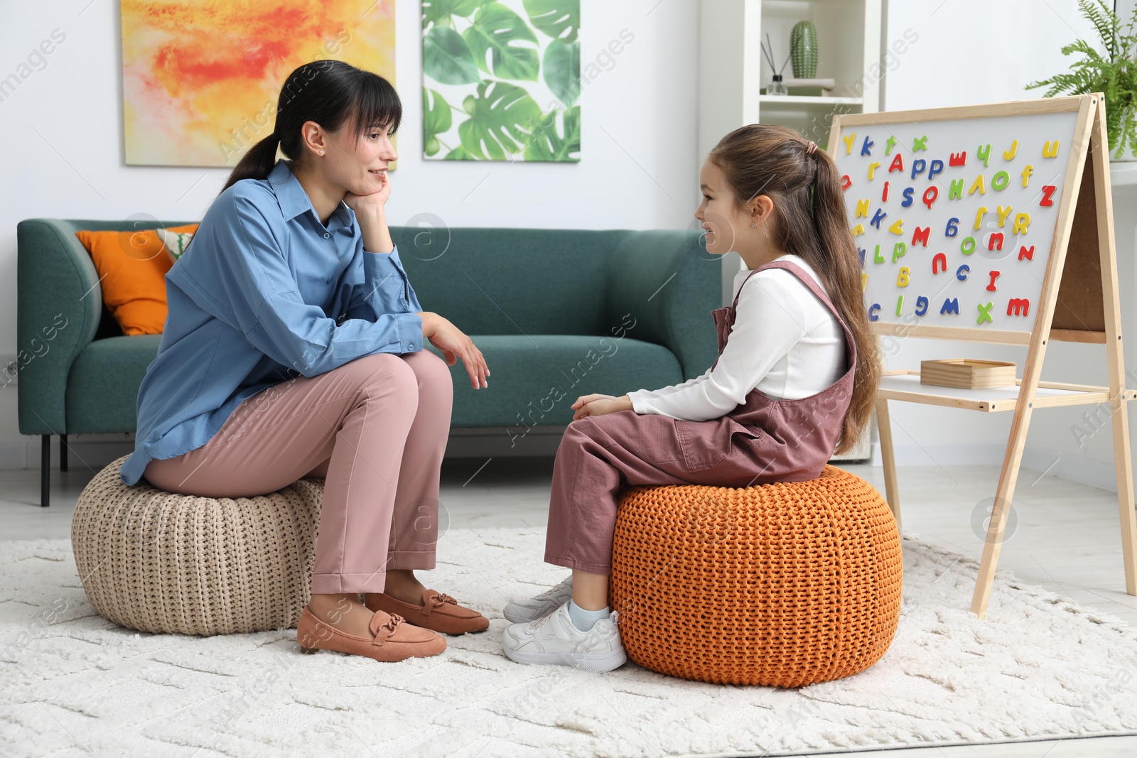 Photo of Little girl having consultation with psychologist in office