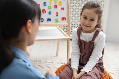 Photo of Little girl having consultation with psychologist in office