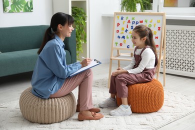 Photo of Little girl having consultation with psychologist in office