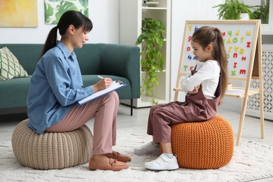 Photo of Psychologist having therapy session with stubborn girl indoors