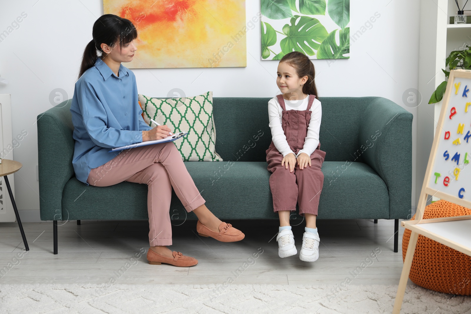 Photo of Little girl having consultation with psychologist in office