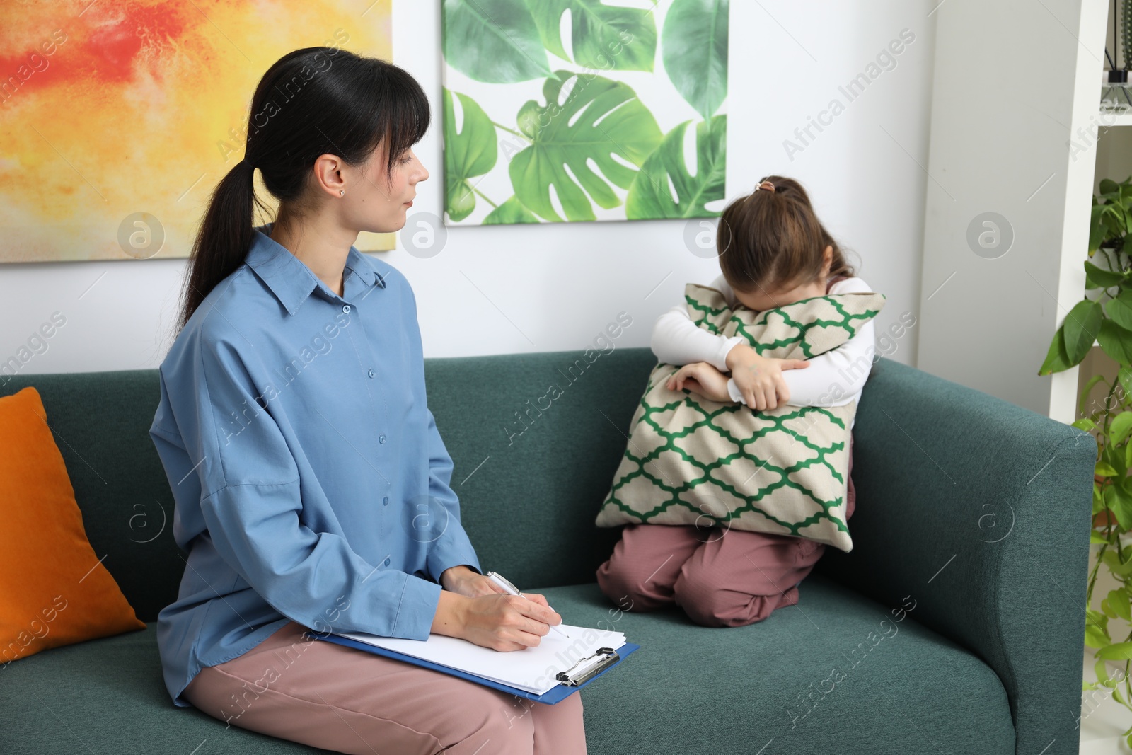 Photo of Psychologist comforting little girl during therapy session indoors