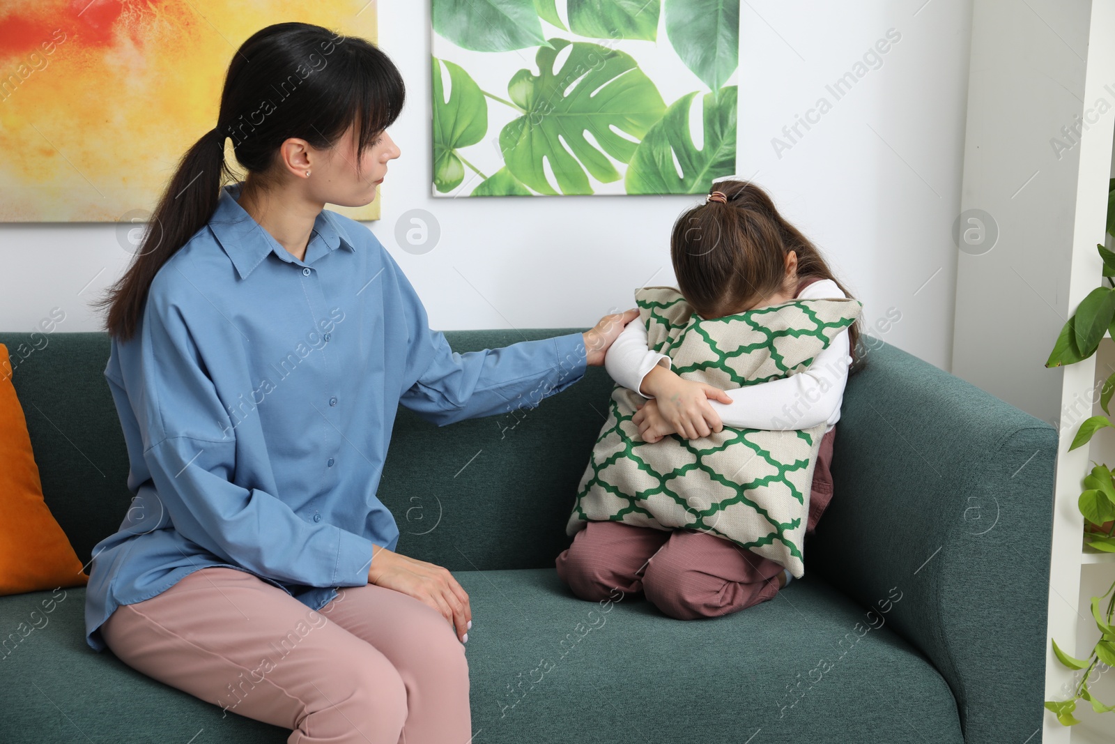 Photo of Psychologist comforting little girl during therapy session indoors