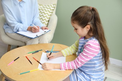 Photo of Little girl drawing during psychological evaluation in office