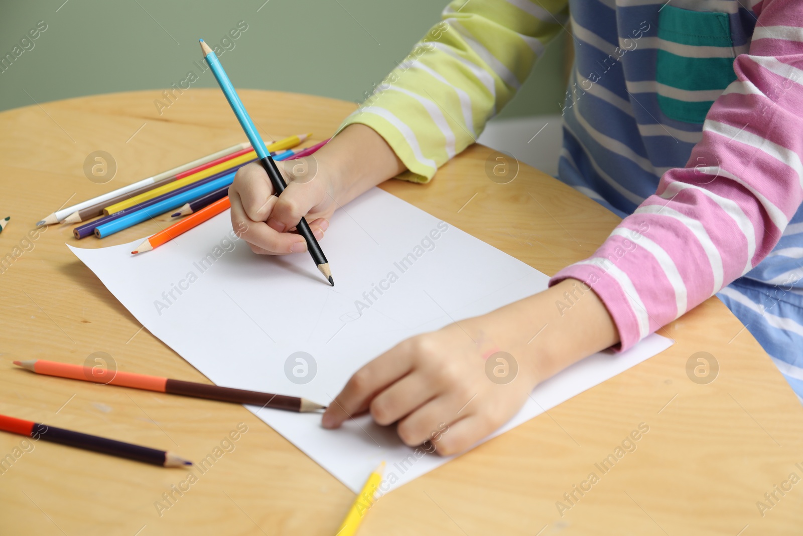 Photo of Child drawing at wooden table in psychologist's office, closeup