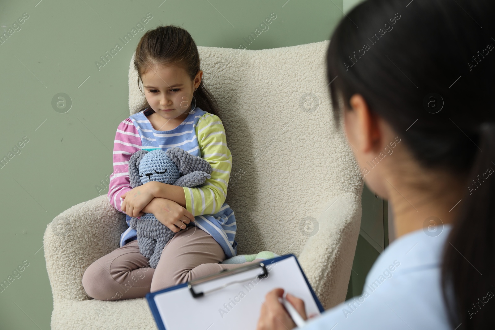 Photo of Psychologist having therapy session with little girl in office, selective focus