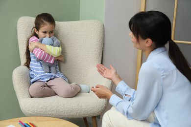 Psychologist having therapy session with little girl in office