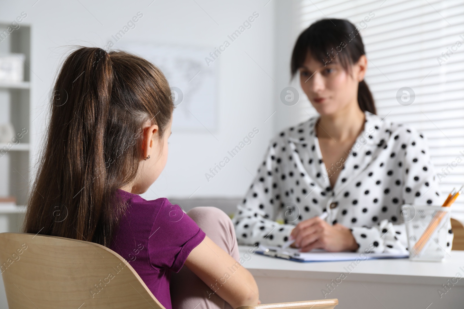 Photo of Psychologist having consultation with girl at desk in office, selective focus