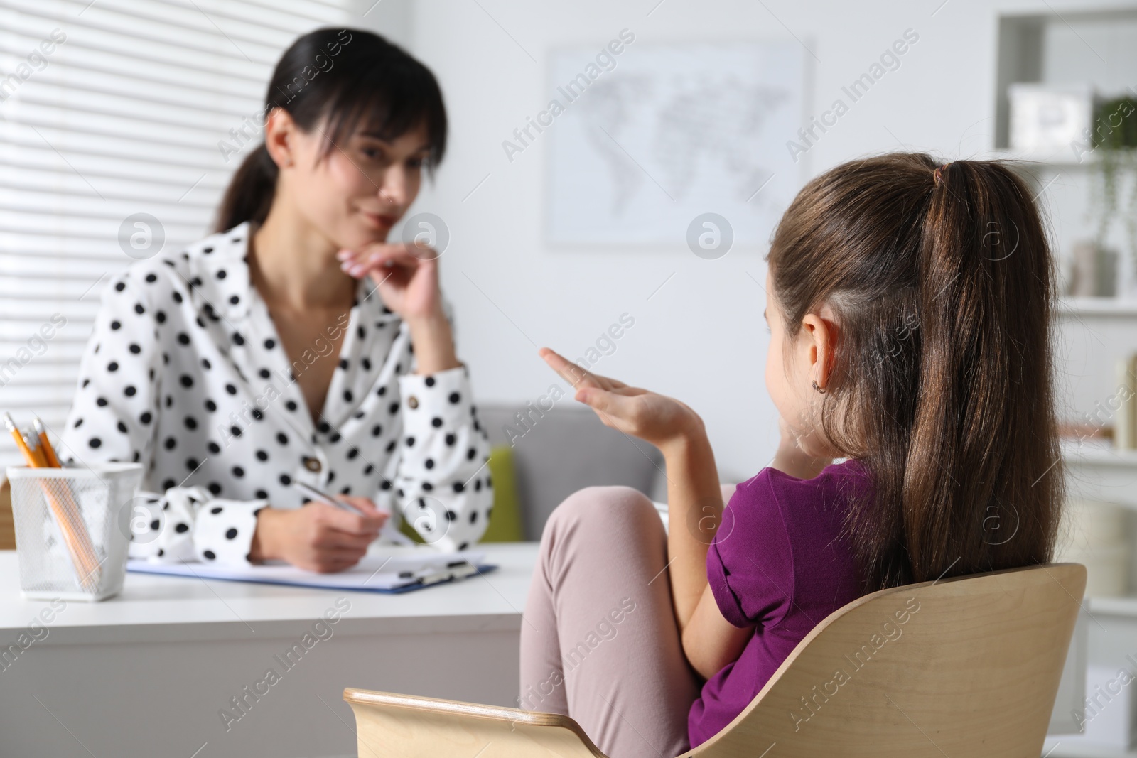 Photo of Psychologist having consultation with girl at desk in office, selective focus