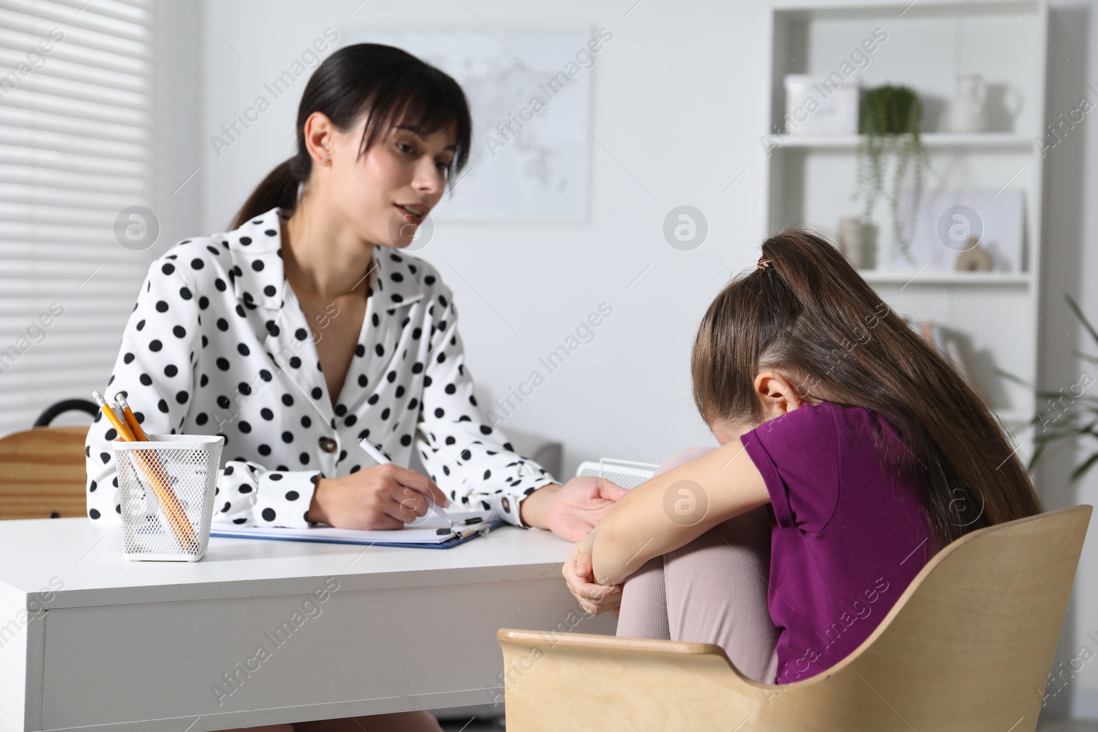 Photo of Psychologist comforting little girl during consultation in office